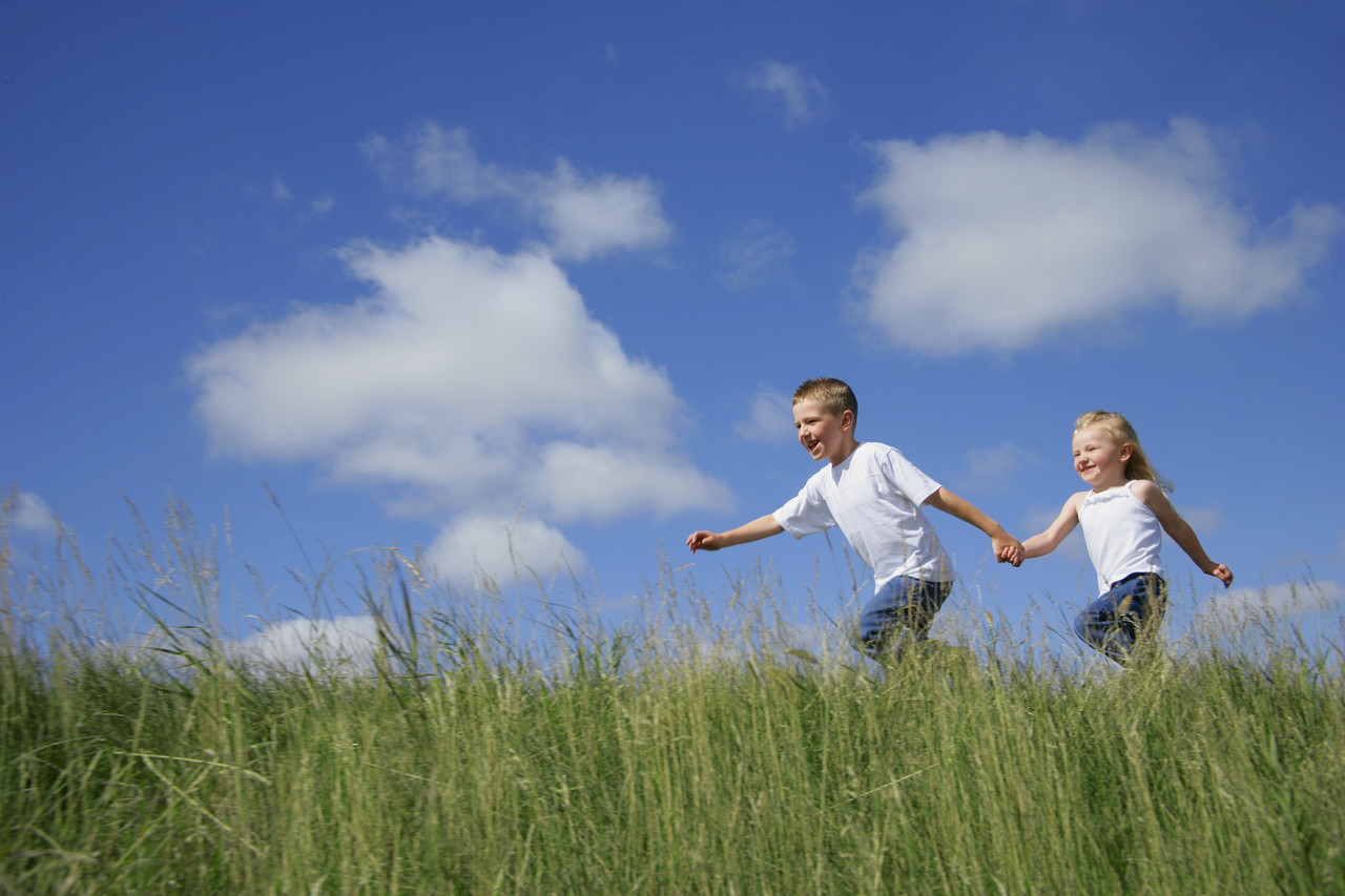 Boy and Girl running through a field of tall Grass